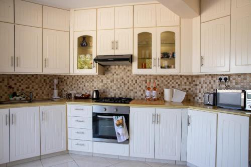 梅内乌Captivating Lake & Oceanview Getaway House的厨房配有白色橱柜和炉灶烤箱。