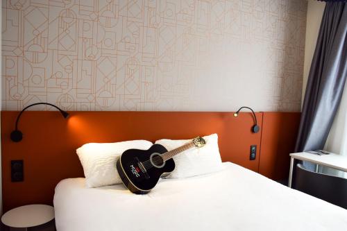 罗德兹宜必思罗德中央酒店的吉他坐在床上