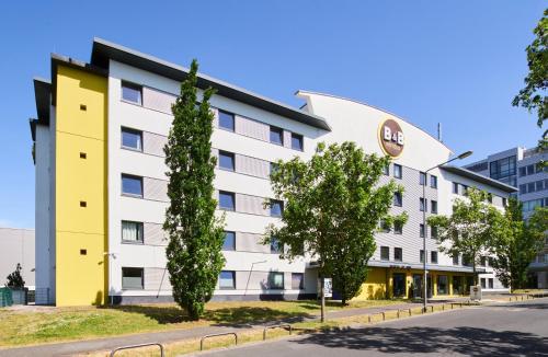 美因河畔法兰克福B&B HOTEL Frankfurt-Niederrad的拥有黄色和白色建筑的酒店