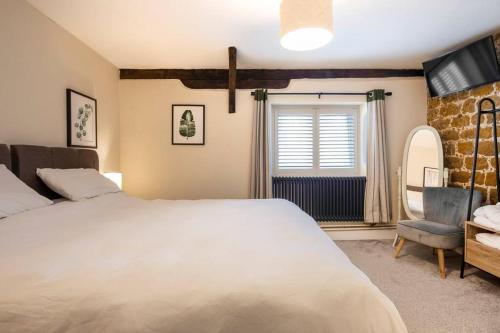 PentneyThe Cart Lodge - relaxing rural spa break的卧室配有一张白色大床和一把椅子