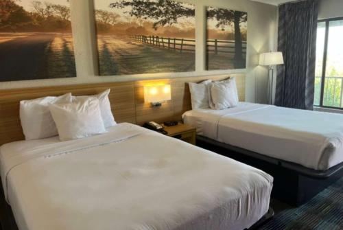 莫比尔提尔曼斯角Days Inn & Suites Mobile的酒店客房设有两张床,墙上挂有绘画作品