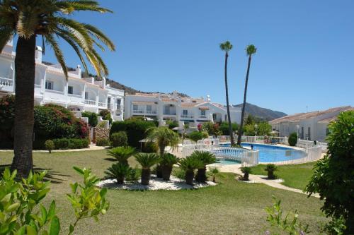 内尔哈JARDINES DE NERJA 18 MENYBER的一个带游泳池、棕榈树和房屋的度假村