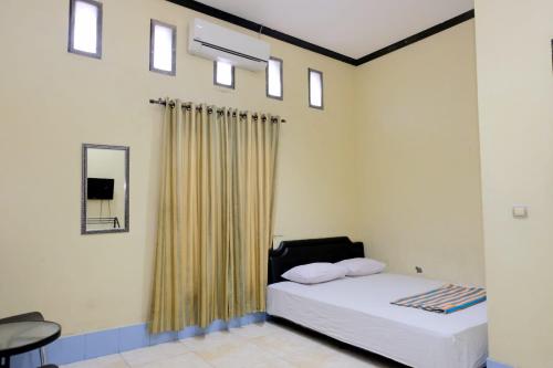 LutanHotel Puri Lembang near Universitas Sulawesi Barat Majene的一间卧室配有一张带窗帘和镜子的床