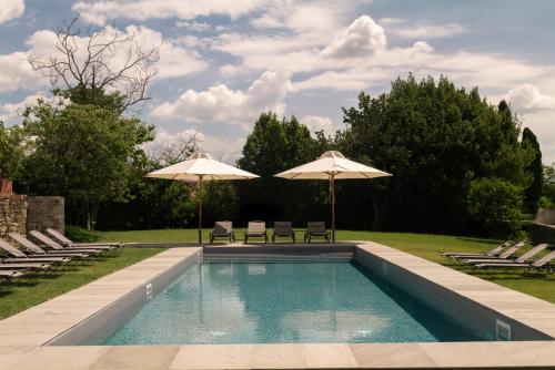 Buttrio布特里奥城堡酒店的一个带两把遮阳伞和两把椅子的游泳池