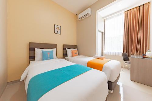 TanjungredepSans Hotel Berau Square的一间卧室设有两张床和窗户。