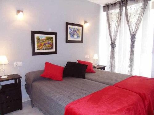 托雷德尔马尔A&N Plaza Sol的一间卧室配有一张带红色枕头的大床