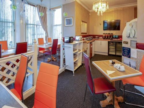 兰迪德诺The Llandudno Hotel的一间带橙色椅子和桌子的餐厅以及一间厨房