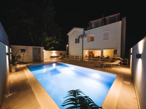 莫斯塔尔Villa Draga的夜间在房子前面的游泳池