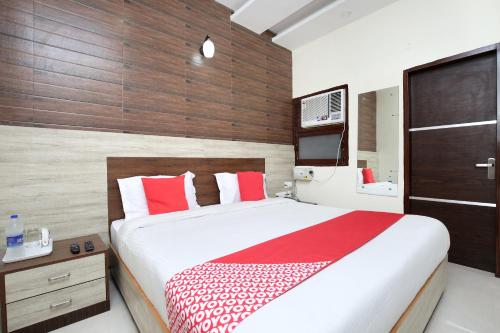 齐拉克普尔OYO Hotel Prabhat的一间卧室配有一张带红色和白色枕头的大床