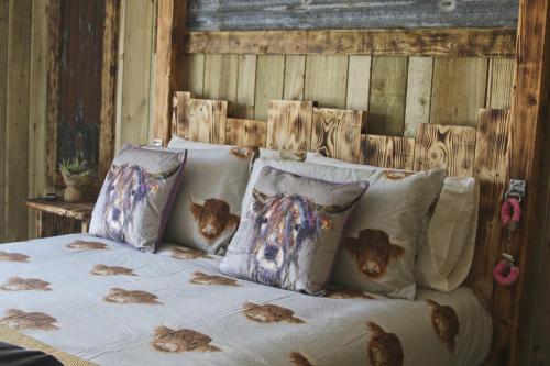 阿博伦The Moo-tel at Bargoed Farm的一张带几个枕头的床,上面有鸡