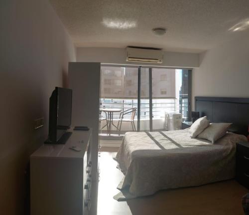蒙得维的亚Edificio Go Pocitos的一间卧室配有一张床、一台电视和一个阳台
