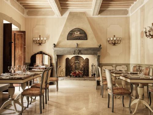 科尔托纳Villa di Piazzano - Small Luxury Hotels of the World的一间带桌椅和壁炉的用餐室