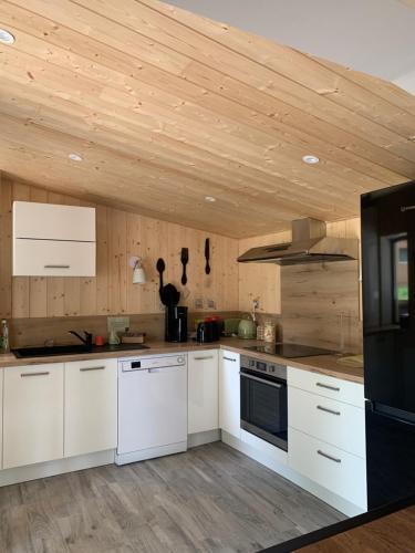 圣阿弗里克La Petite Auberge Insolite的厨房配有白色橱柜和木制天花板