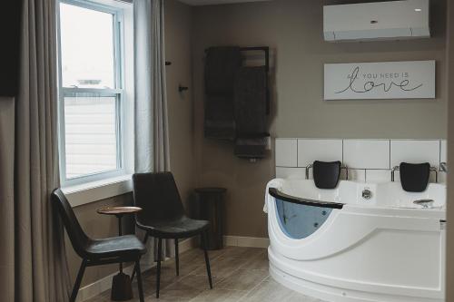 温莎大瀑布河滨套房公寓的带浴缸和两把椅子的浴室以及窗户。