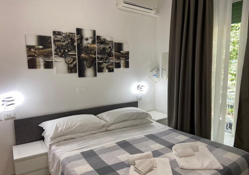 里米尼chiAma Hotel的卧室配有一张四幅画的墙壁床。
