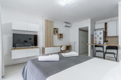 米兰Santa Giulia Suite的白色卧室设有一张大床和电视。