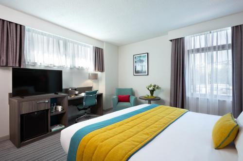 布莱顿霍夫Leonardo Hotel Brighton的酒店客房配有一张床、一张书桌和一台电视。