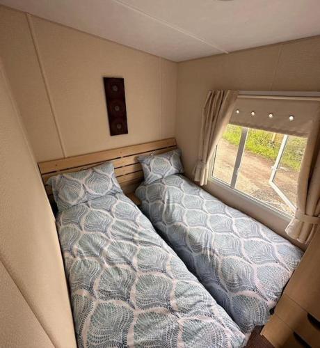 阿丁斯顿4-Bedroom Cosalt Parkhome in Uddingston, Glasgow的一间大篷车卧室,配有两张床和窗户