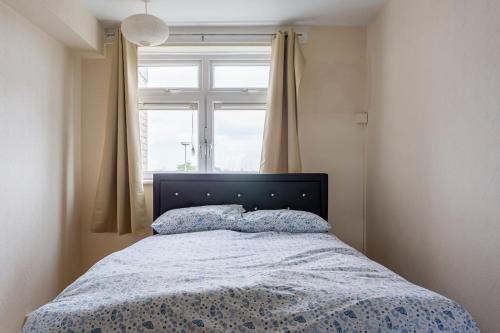 伦敦Home From Home的一间卧室配有一张带蓝色棉被的床和窗户。