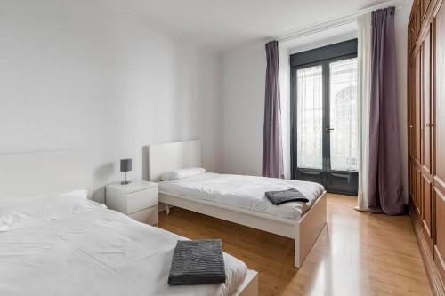 马德里AVE Apartamento Madrid Centro Atocha的一间白色卧室,配有两张床和窗户