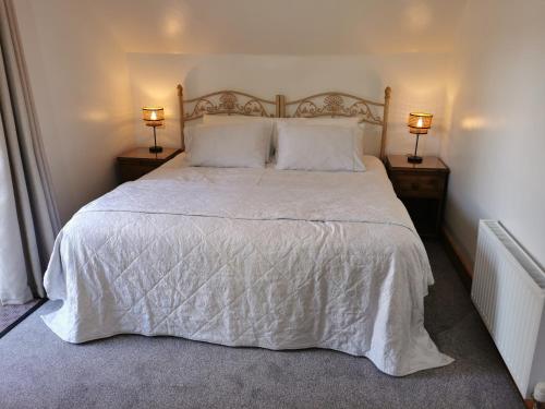 伍尔弗汉普顿The Sanctuary at Boningale Manor的一间卧室配有一张带两盏灯的大型白色床。