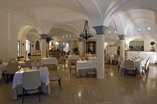 阿马尔菲公馆酒店的餐厅配有白色的桌椅和吊灯