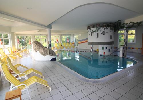 Grafendorf bei HartbergWohlfühl Hotel Wiesenhof的一个带黄色椅子的大型游泳池和一个游泳池