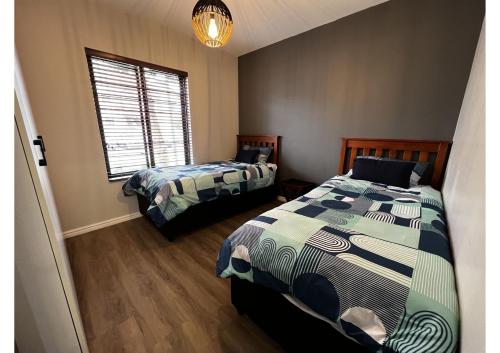 开普敦Mo's Explorer Cape Town Vacation Apartment的一间卧室设有两张床和窗户。
