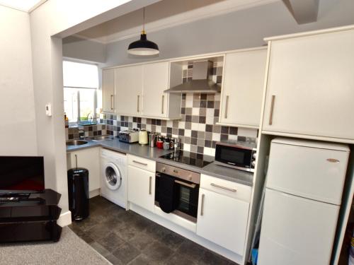 切尔滕纳姆Stephen's Cheltenham apartment的厨房配有白色橱柜和洗碗机。