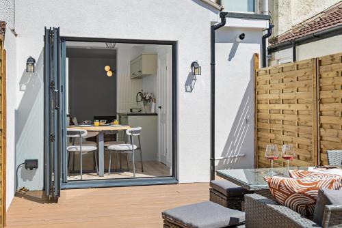 朴次茅斯Cosy & Bright Home with Backyard in Southsea Portsmouth的一个带桌椅的庭院和一扇通往厨房的门