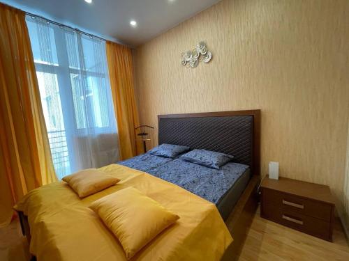 里加Quiet 1BR in Serene neighborhood的一间卧室配有一张带黄色床单的床和一扇窗户。
