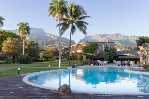 帕皮提皇家塔赫缇恩酒店的一座棕榈树和山脉环绕的游泳池