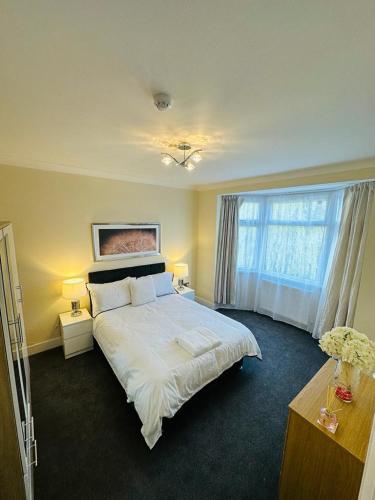 伍德福德格林4 Bed Family Home的卧室设有一张白色大床和一扇窗户。