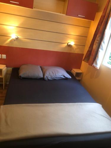 Saint-ChéronCamping Parc des Roches-Mobilhome的小房间的一个床位,配有两个枕头