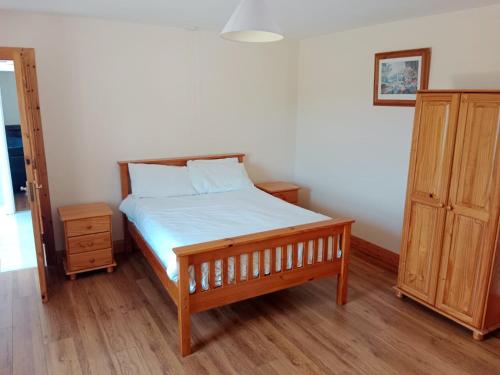 米尔福德Willowfarmhouse的一间卧室配有一张床和一个木制橱柜
