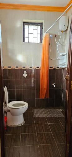 蒙巴萨Betty Homes的浴室设有卫生间和橙色淋浴帘