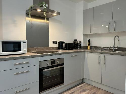 曼彻斯特Lovely Entire Flat in Manchester的厨房配有白色橱柜和微波炉