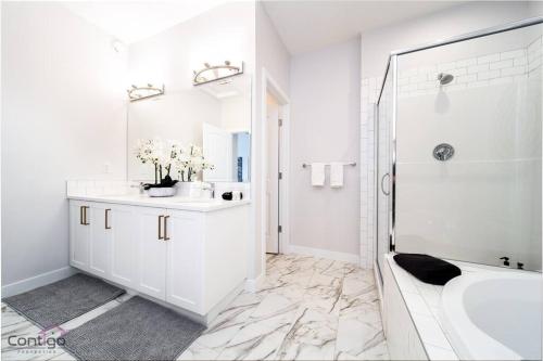 埃德蒙顿Boho Luxe Home, Sleeps 12, AirCon, King Bed, WiFi的白色的浴室设有浴缸和水槽。