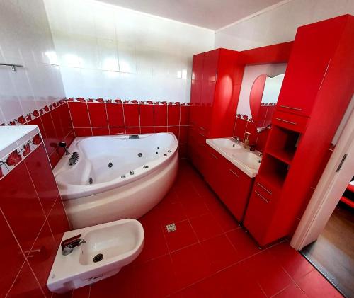 GhioneaAlpha Pool House的红色的浴室设有浴缸和水槽