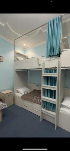 塔什干LOONA FAMILY HOSTEL的客房设有两张双层床和蓝色窗帘