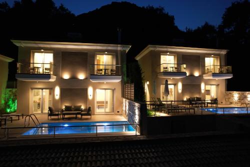 帕尔加Elais Luxury Villas的一座白色的大建筑,晚上设有游泳池
