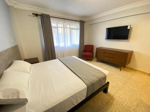 科恰班巴Izza Hotel的一间卧室配有一张床和一台平面电视