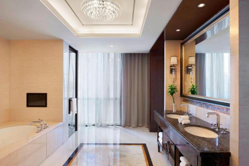 武汉武汉富力威斯汀酒店的浴室配有2个盥洗盆、浴缸和大镜子