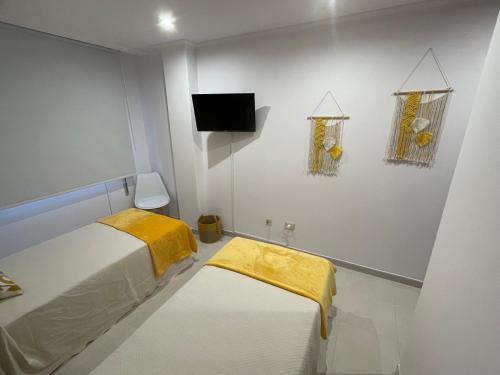 格罗韦Apartamentos Demar Luis Casais的一间白色的小房间,配有床和电视