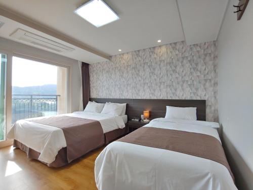 西归浦市Jeju Lavender Hotel的一间卧室设有两张床和大窗户