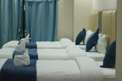 贾纳克布尔Hotel Sara PVT LTD的客房配有4张带蓝色枕头的白色床。