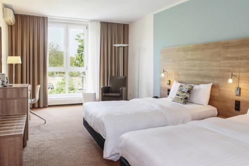 德累斯顿德累斯顿德勒斯登万怡酒店的酒店客房,配有两张床和椅子