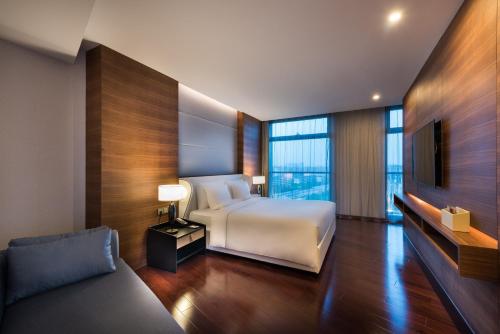 上海上海建滔诺富特酒店的一间卧室配有一张床、一台电视和一张沙发