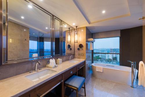 上海上海建滔诺富特酒店的一间带两个盥洗盆和浴缸的浴室以及大窗户。