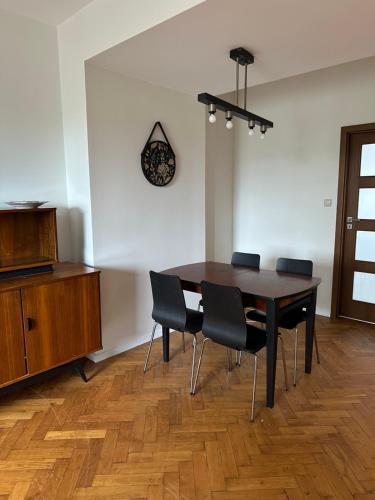 格丁尼亚Apartament Syrokomli 3的餐桌、椅子和墙上的时钟